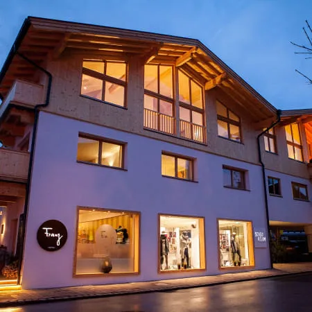 Moderne Gebäudeansicht mit Holzfassade und beleuchteten Fenstern
