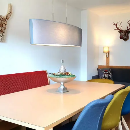 Moderne Esszimmer mit roter Bank, blauem Sofa und dekorativen Geweihen.