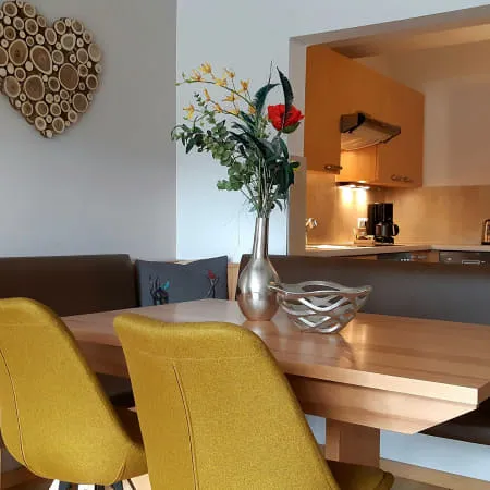 Wohnzimmer mit Esstisch, Stühlen und modernen Küchenelementen.