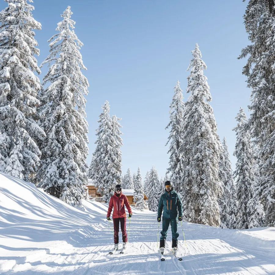 Zwei Skifahrer in einer schneebedeckten Winterlandschaft.