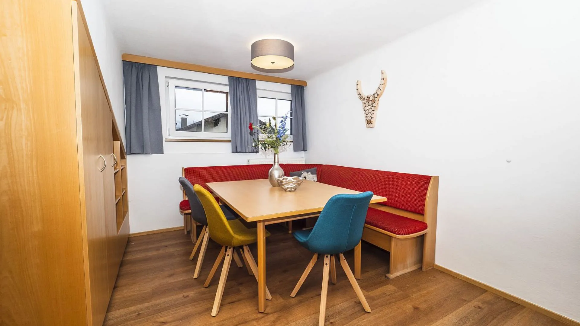 Gemütlicher Essbereich mit Holztisch und bunten Stühlen