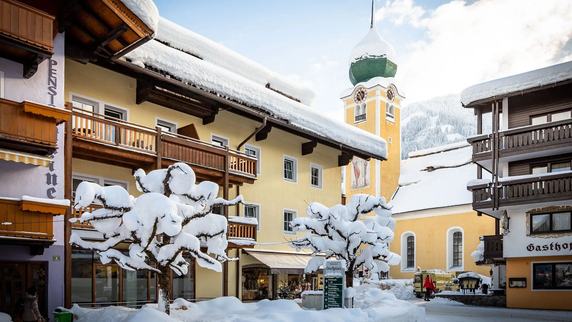Schneebedeckter Dorfplatz mit Gebäuden und Kirchturm
