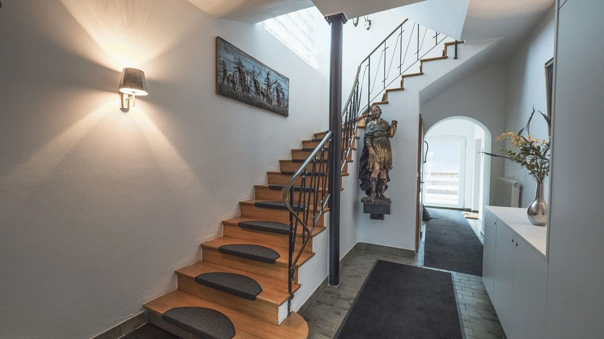 Eingangsbereich mit Treppe und Skulptur an der Wand